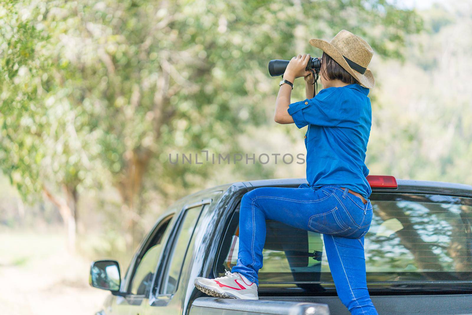 Close up Young asian woman short hair wear hat and hold binocular in grass field countryside Thailand
