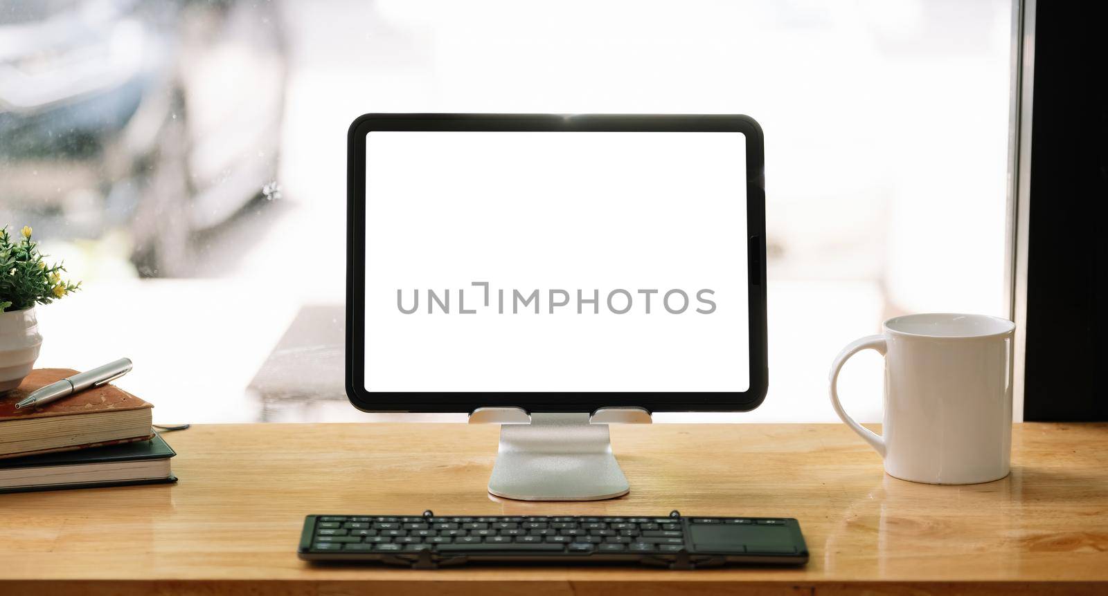 Portable workspace with blank screen tablet on wooden desk with copy space and decorations in coffee shop