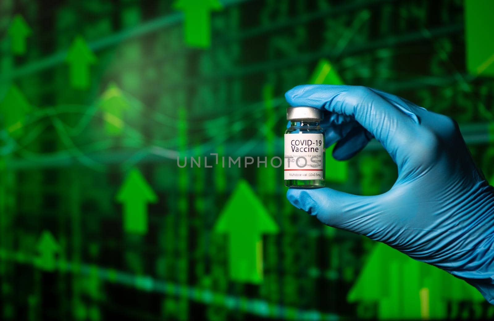 Hands of a researcher in medical gloves holding a Coronavirus Vaccine  with stock index chart rising up in the background.