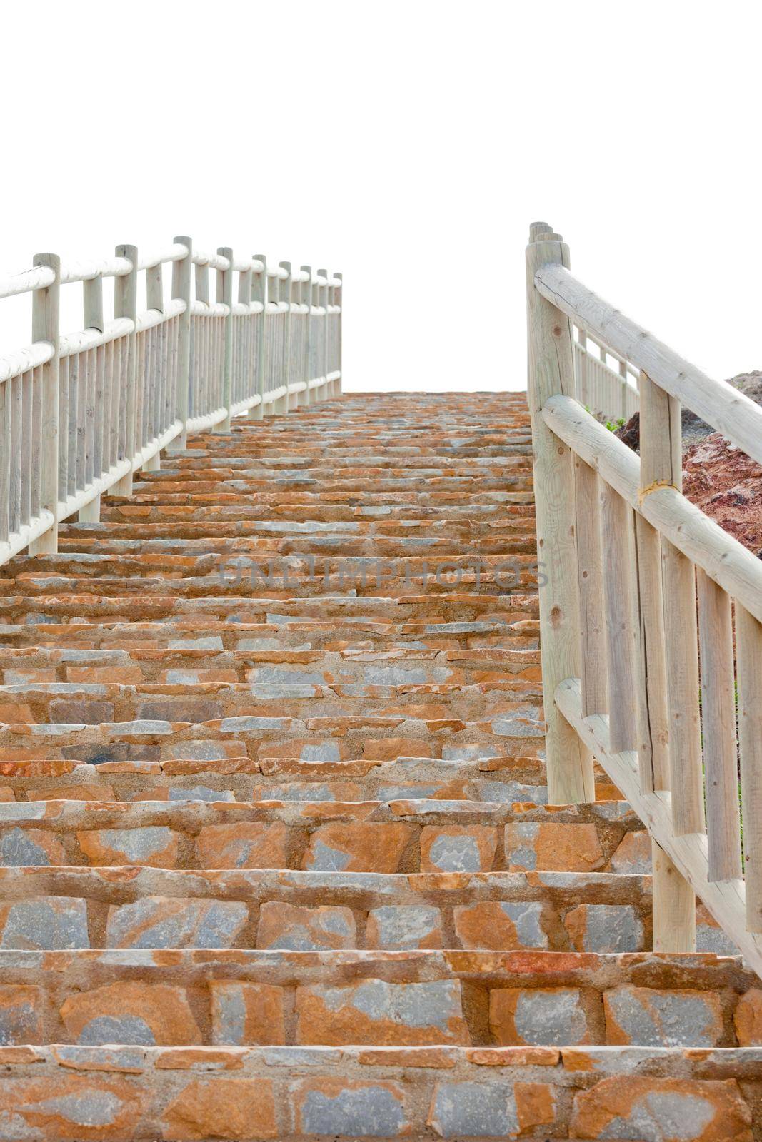 View from the bottom of a steep flight of brick steps with wooden railings leading up to the skyline