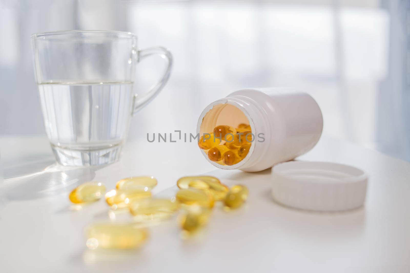 healthy lifestyle, medicine, nutritional supplements and people concept - close up of male hands holding pills with cod liver oil capsules and water glass by mihavincadani