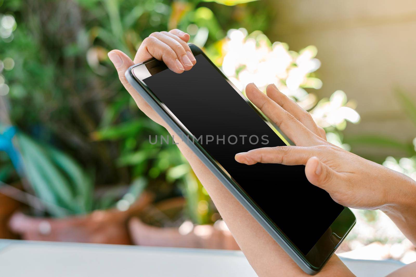 Woman's hand is touching on the black screen of the tablet, using technology and social media concepts.
