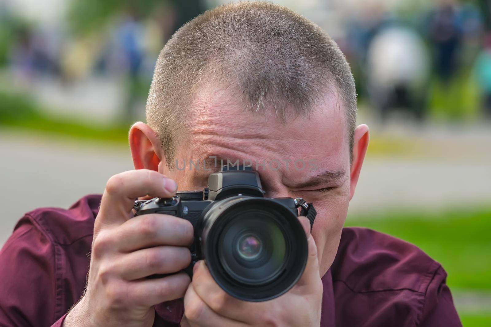 Close up portrait of photographer during the process of shooting work on camera outdoors