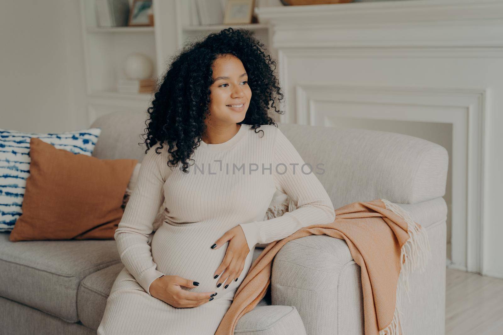 Beautiful young mixed race pregnant woman hugging her tummy by vkstock