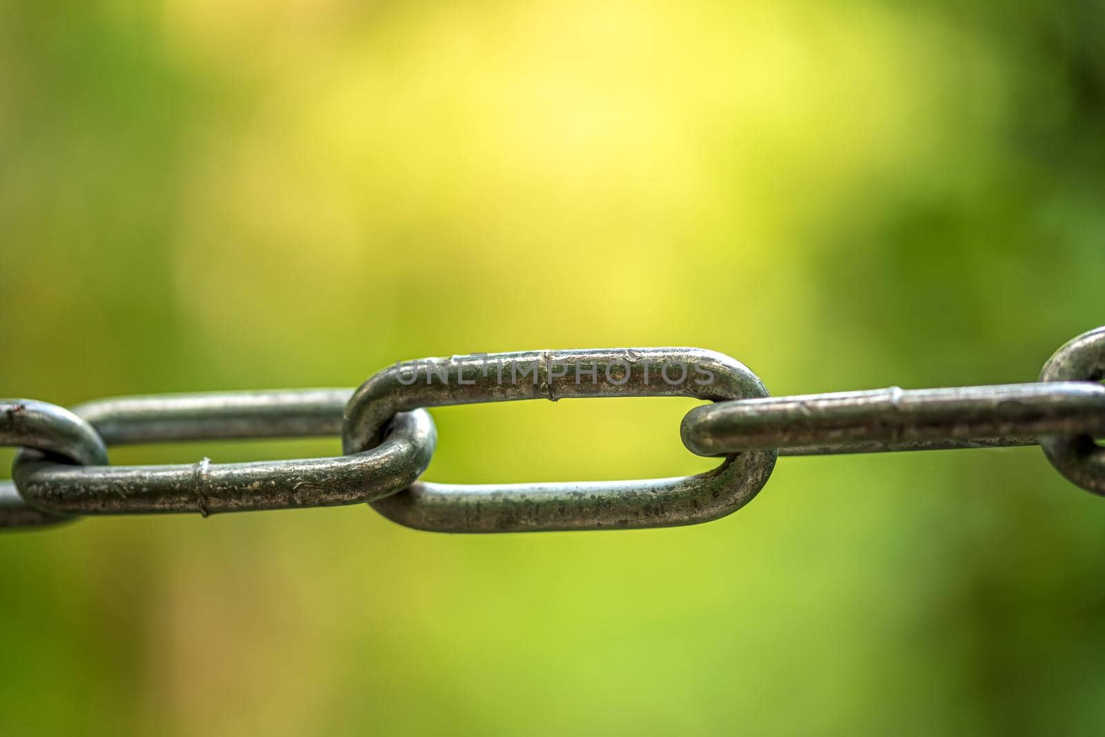 Small fragment of a metal chain against the background of brightly green