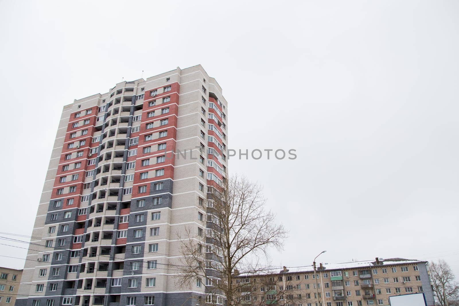 Residential high-rise building in a residential area of the city. Against the background of the gray sky. Modern new buildings, building facades. Real estate and urban architecture concept.