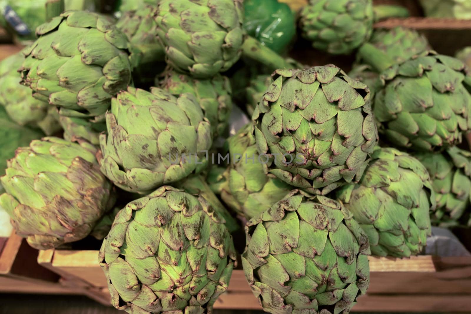 Fresh green artichoke in wooden box on the market by Estival