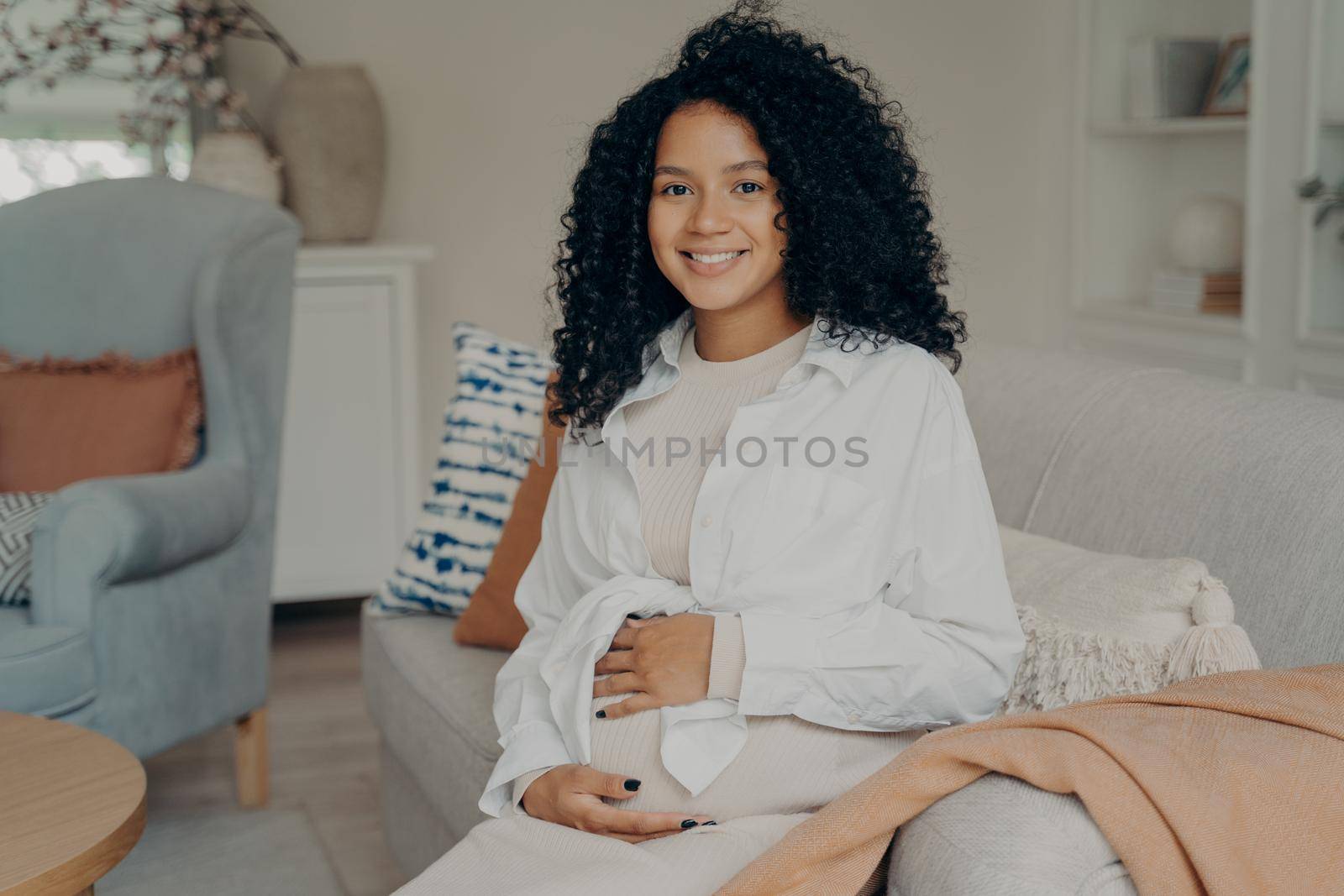 Cute mixed race pregnant lady with curly hair enjoying wonderful time of pregnancy by vkstock