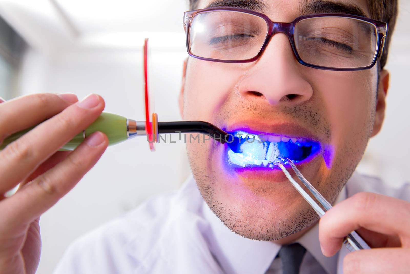 Funny dentist with curing light in medical concept by Elnur