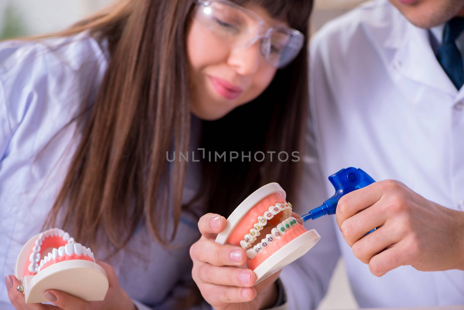 Dentist explaining brackets ligature setting by Elnur