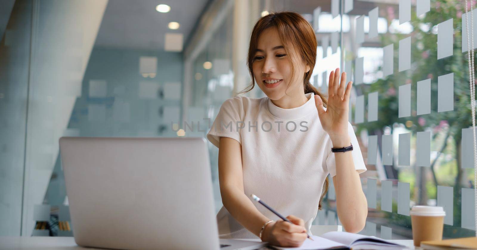 Young female college taking notes and using highlighter. Focused student in online class room. Authentic Education concept. by itchaznong