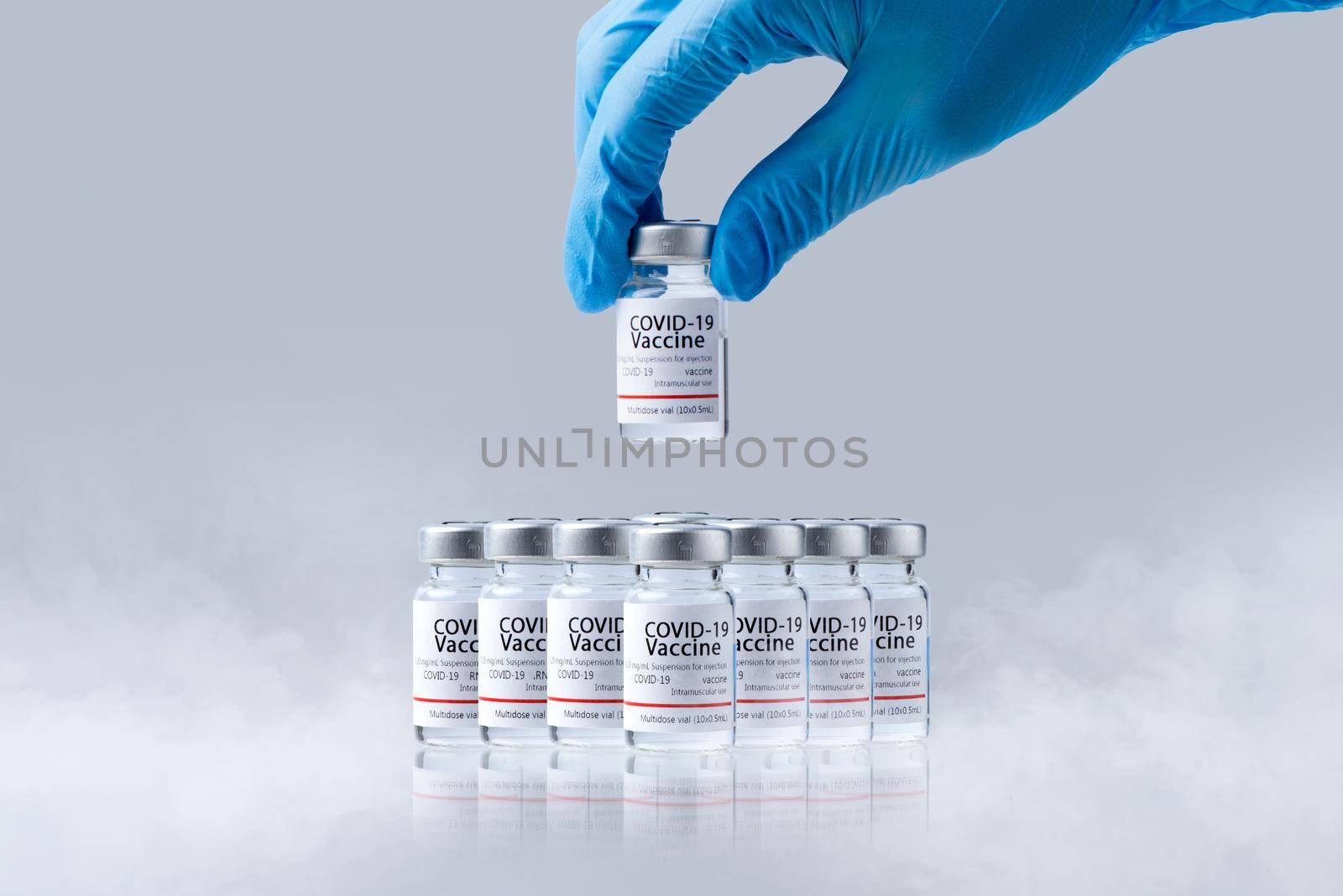 Hand holding frozen cold Vaccine vials for Covid-19 vaccine in laboratory. Group of Coronavirus vaccine bottles.