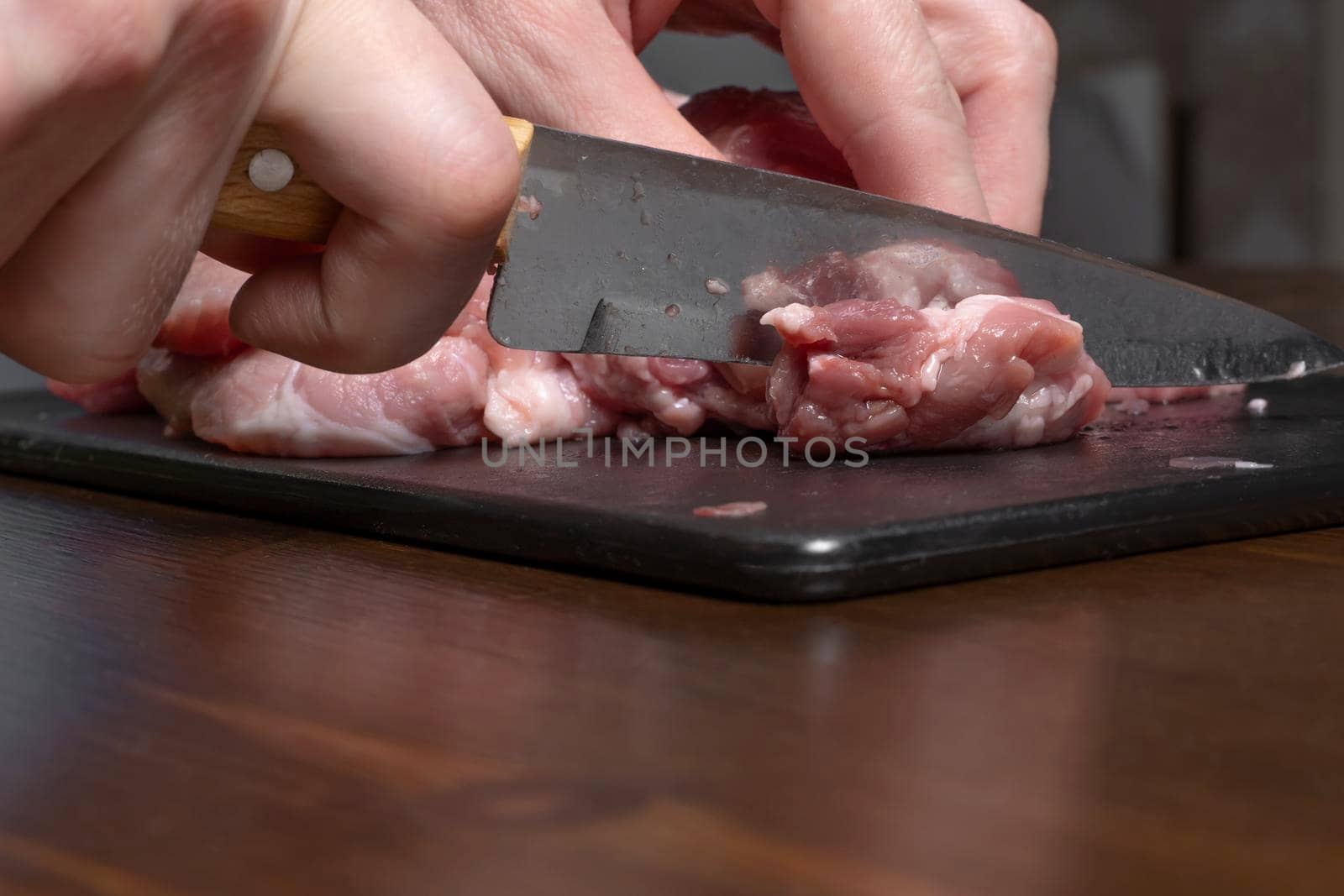 Slice the pork or beef with a knife on the table in close-up.Preparation of meat dishes and food products.Pieces of red meat for shish kebab,barbecue or kebab.Raw fresh meat is cut with a knife.recipe