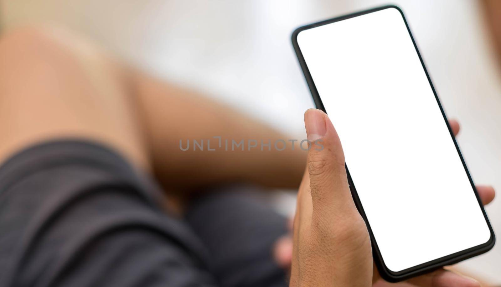 Mockup image blank white screen cell phone.men hand holding texting using mobile on desk at home office..