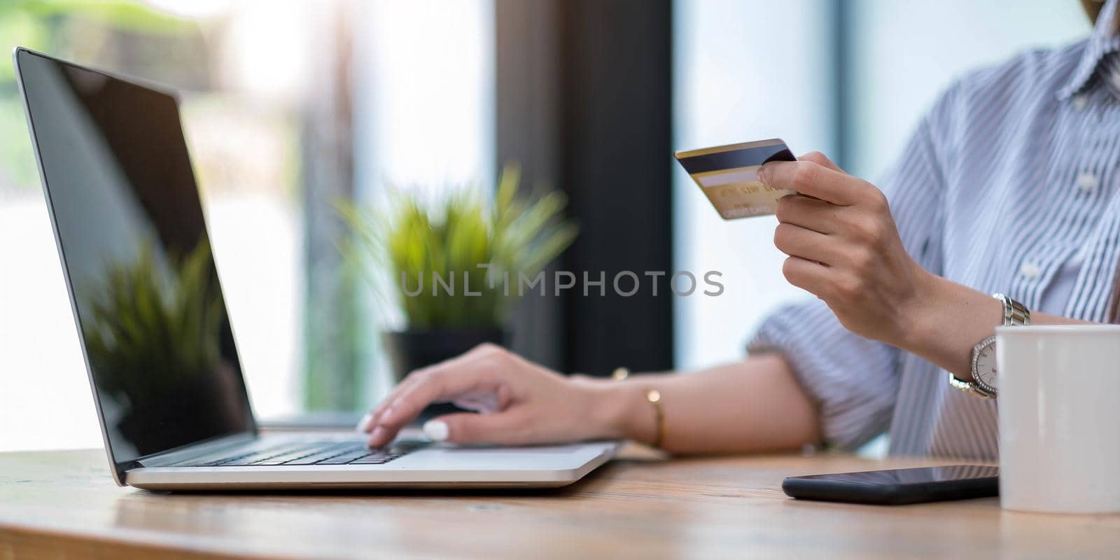 Online payment,Young woman's hands using computer and hand holding credit card for online shopping by wichayada