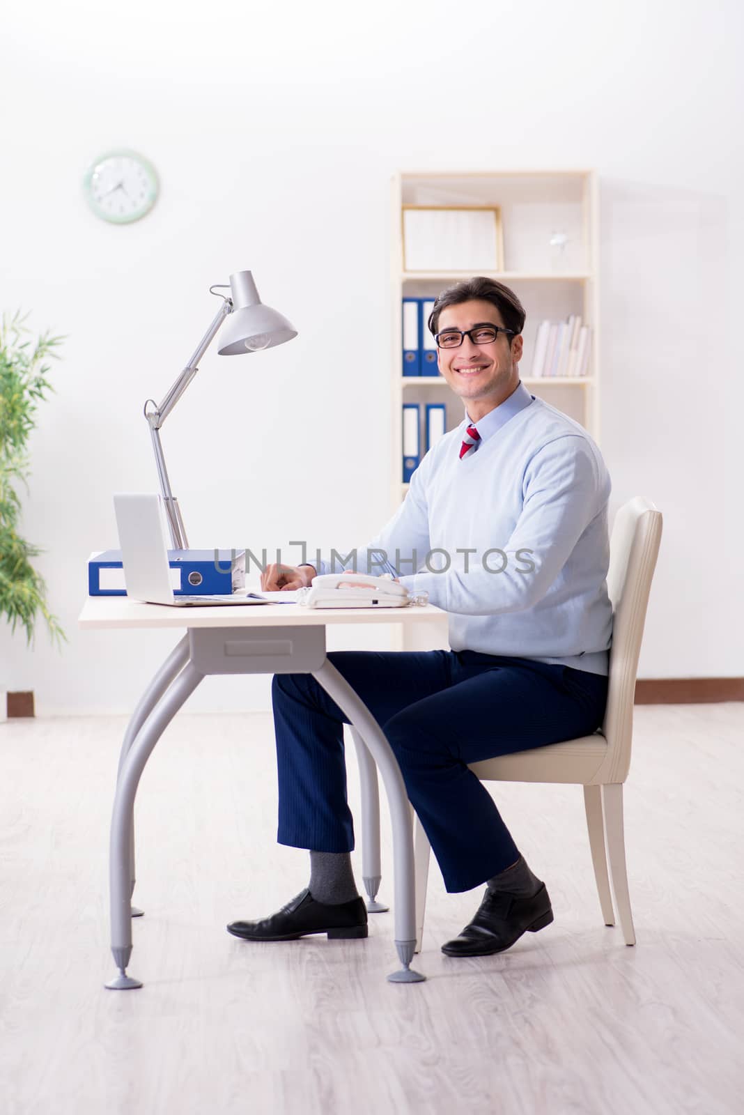 Young handsome businessman employee working in office at desk