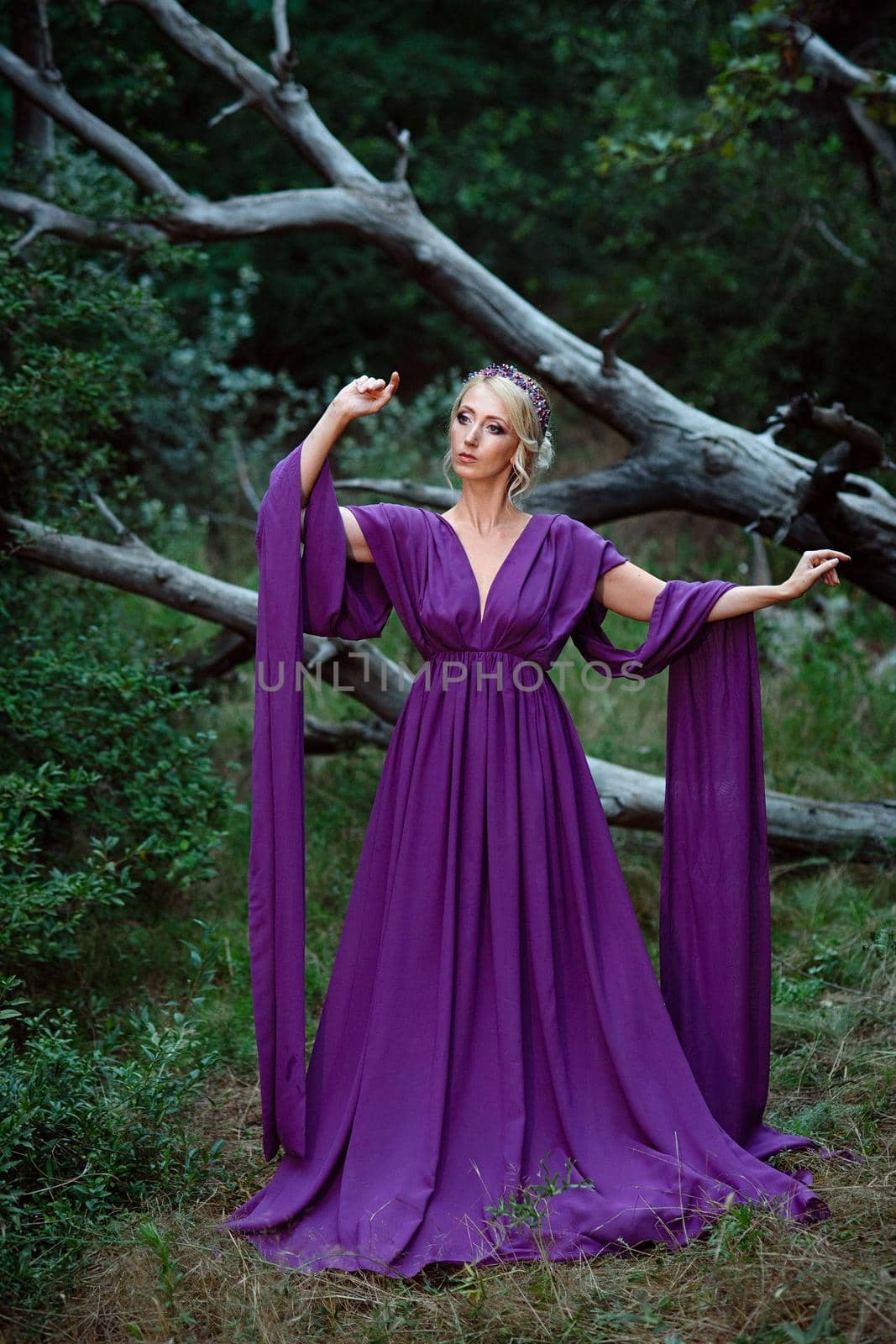 Girl model blonde in a lilac dress with a bouquet with a green forest