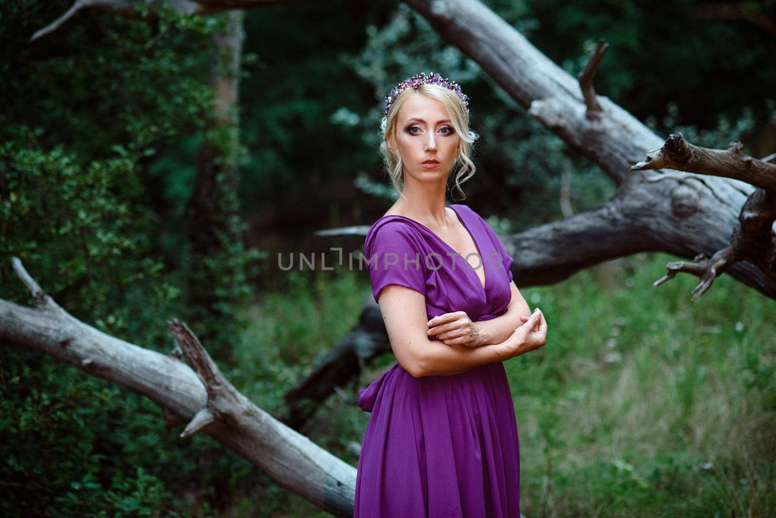 Girl model blonde in a lilac dress with a bouquet with a green forest