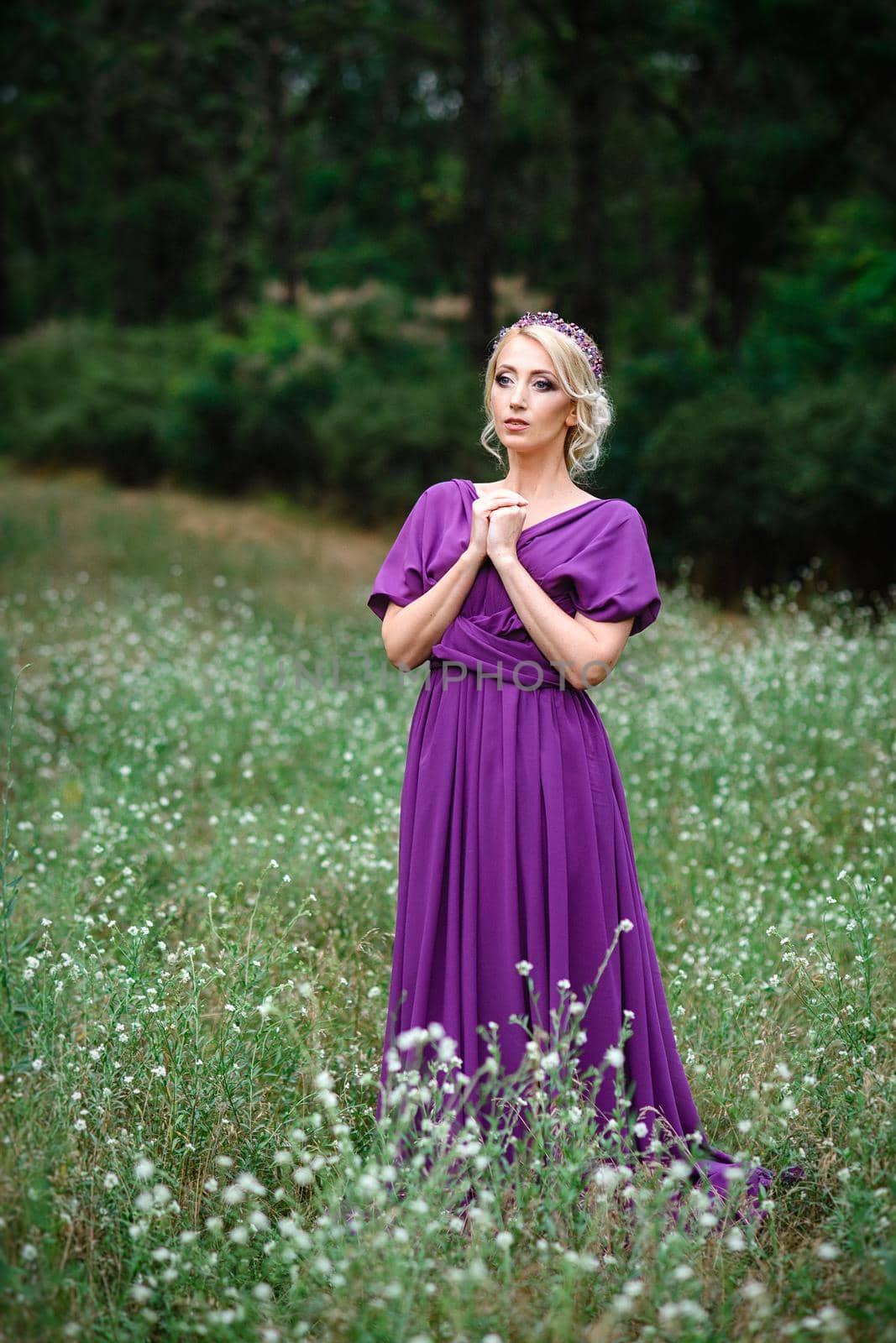 Girl model blonde in a lilac dress with a bouquet with a green forest