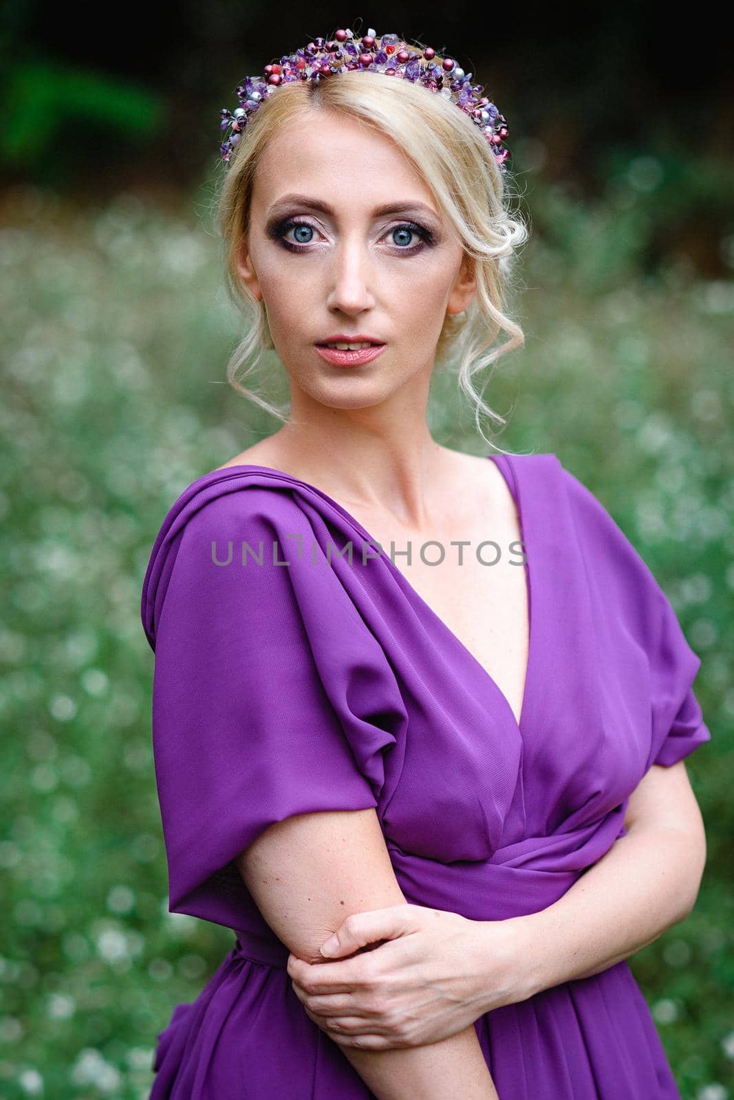 Girl model blonde in a lilac dress with a bouquet with a green forest