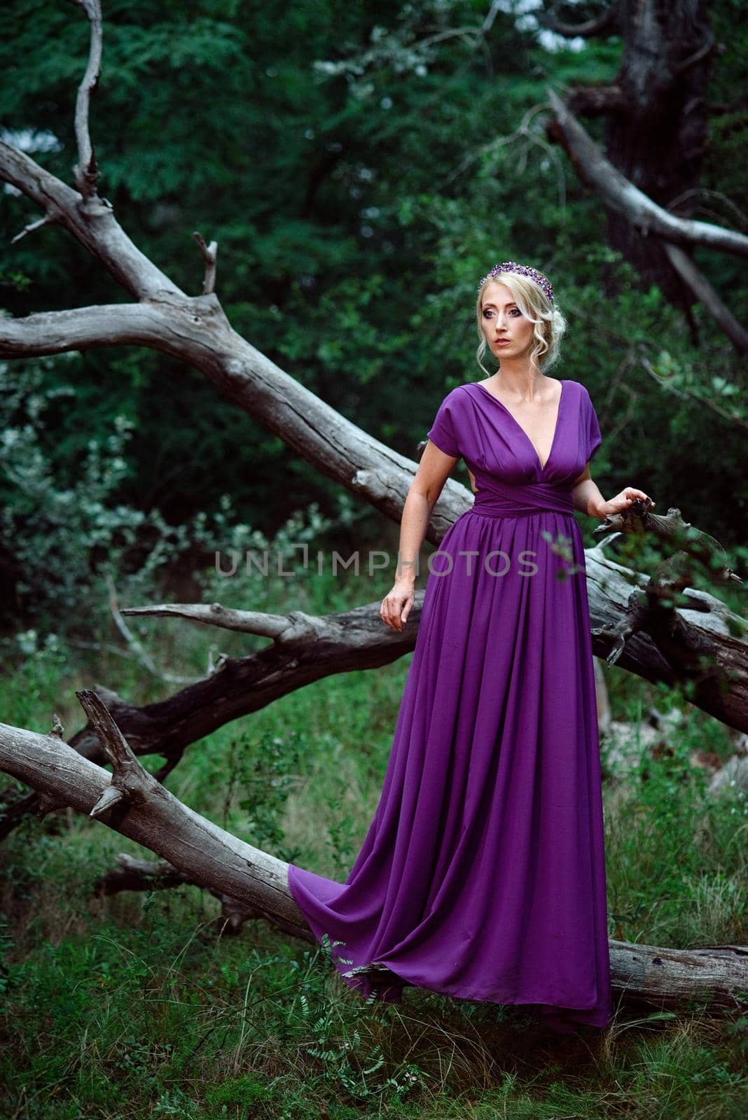 Girl model blonde in a lilac dress with a bouquet with a green forest