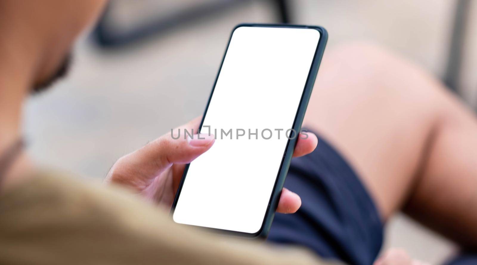 Mockup image blank white screen cell phone.men hand holding texting using mobile on desk at home office..