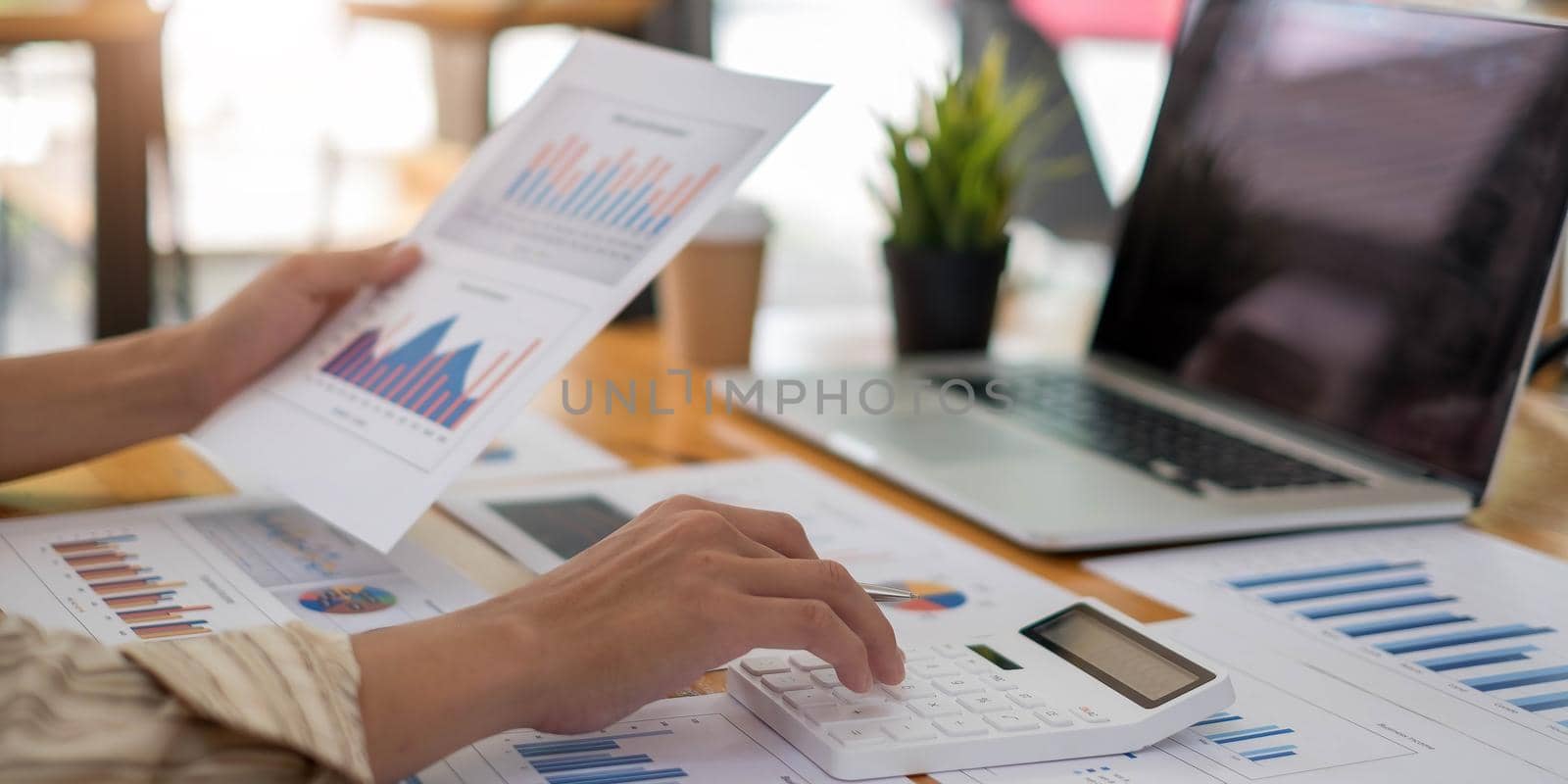 Close up hands businessman doing finances with using calculator and point to Market Graph in home office by wichayada