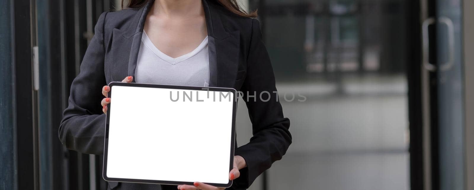 Close-up shot on blank tablet computer showing businesswoman with two hands in a conference room