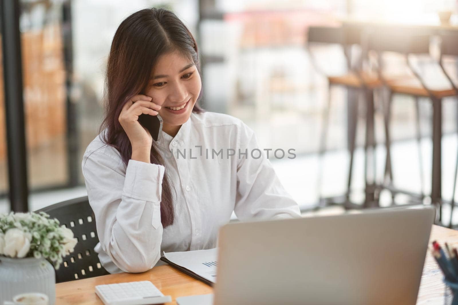 Young businesswoman speaking on the phone whilte using laptop computer at meeting room. business team working together via online distance.