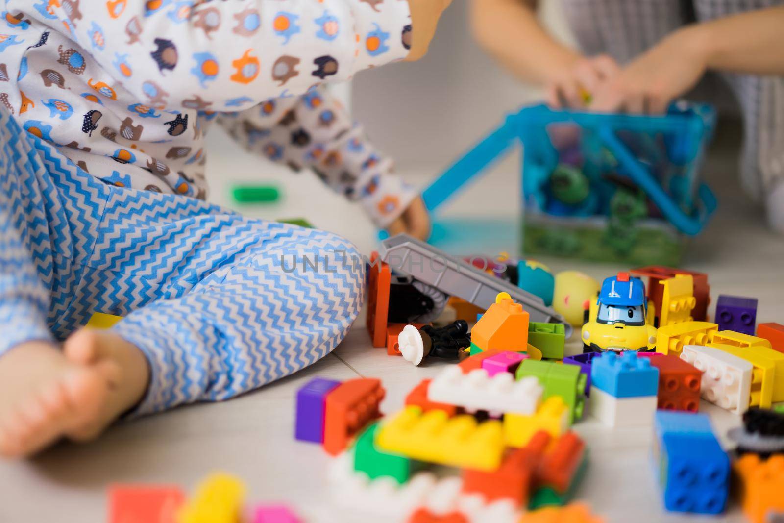 boy child playing with his mother in color children's building kit. The details of the children's building kit are scattered on the floor.