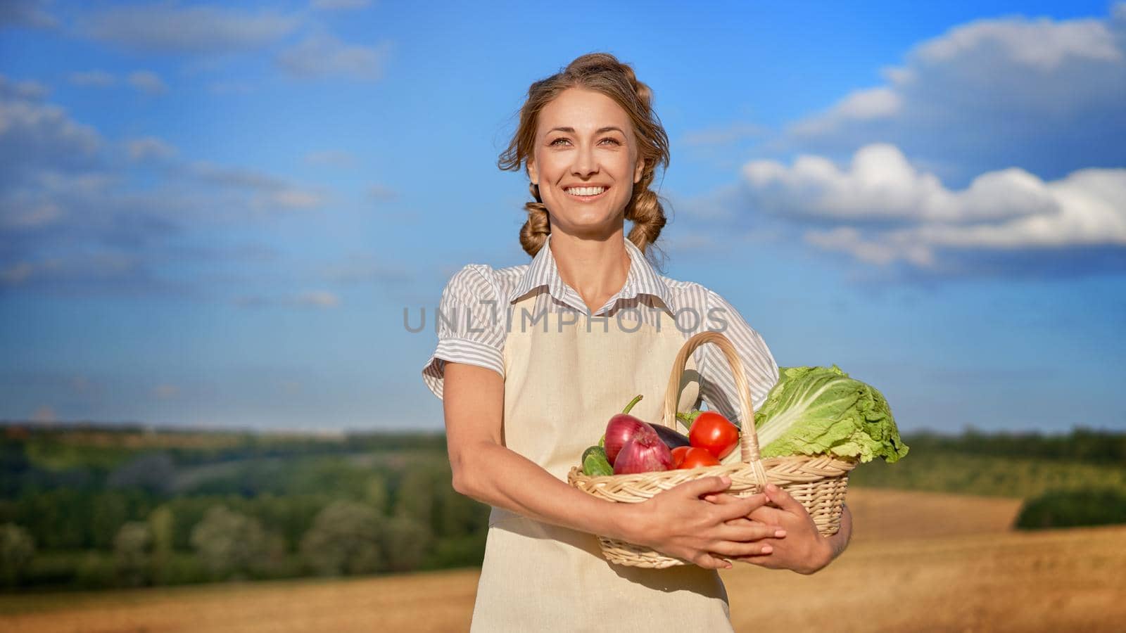 Woman farmer holding basket vegetable onion tomato salad cucumber standing farmland smiling Female agronomist specialist farming agribusiness Happy Girl dressed apron cultivated wheat field