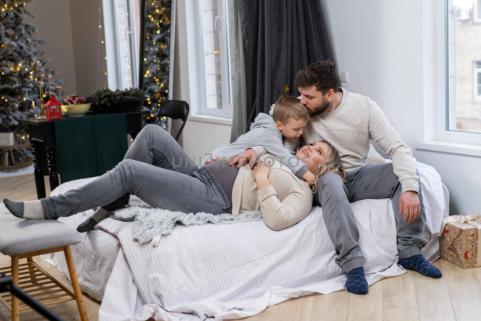 Happy family concept Mother father and little son have fun at home Caucasian family indoors Pregnant mom beard dad and funny little boy lie on the couch