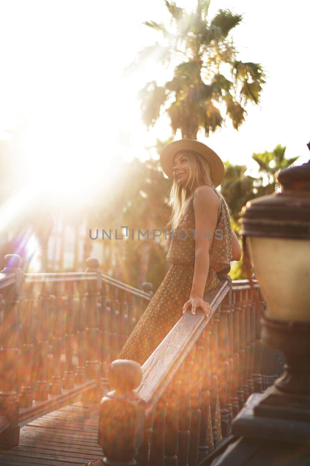 Portrait of a young blonde in a hat on a tropical background. Sunny light and bright colors. Blurred photo in sunlight
