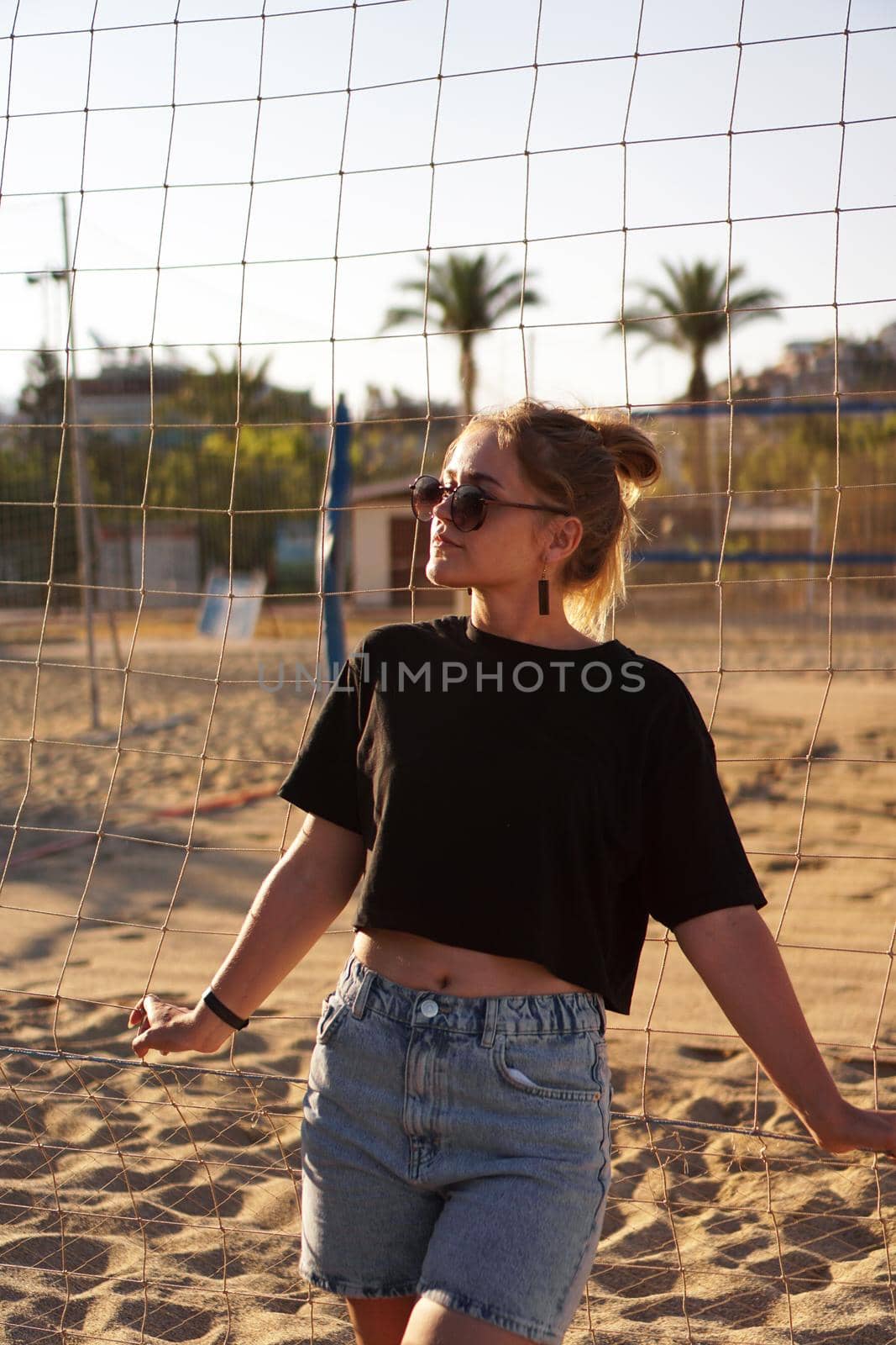 Portrait of attractive woman near volleyball net on the beach. Vertical photo by natali_brill