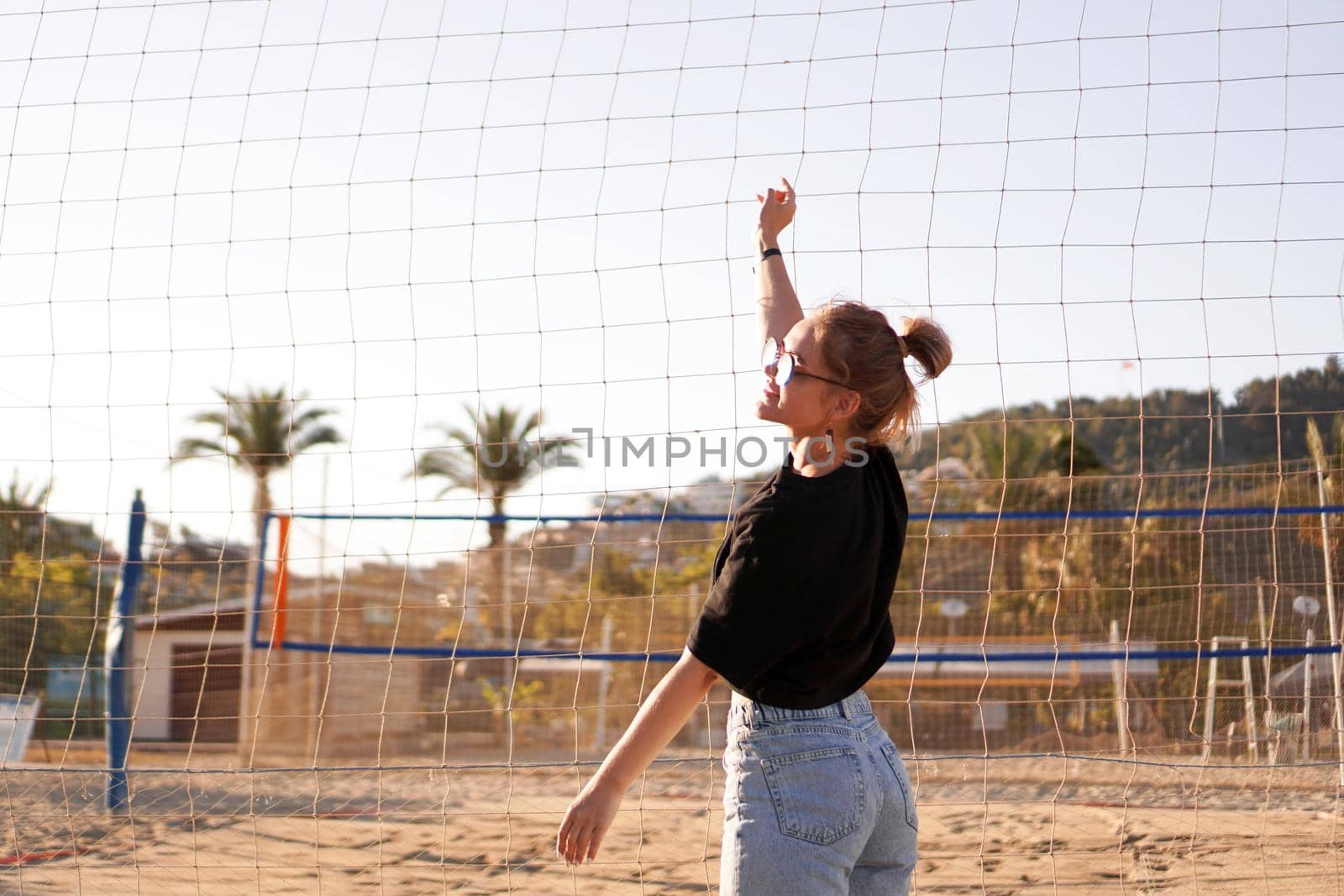 Portrait of attractive woman near volleyball net on the beach by natali_brill