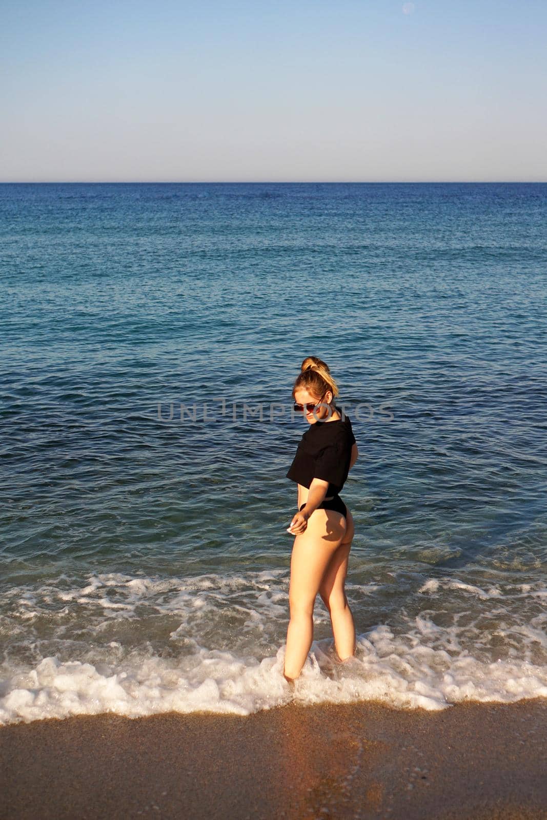 Young woman in a black tank top and underpants on the sea beach by natali_brill