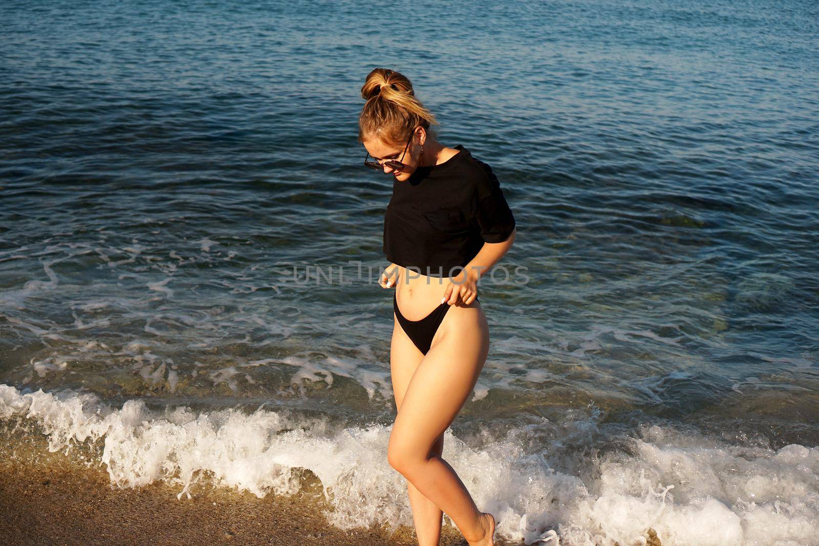 Young woman in a black tank top and underpants on the sea beach by natali_brill