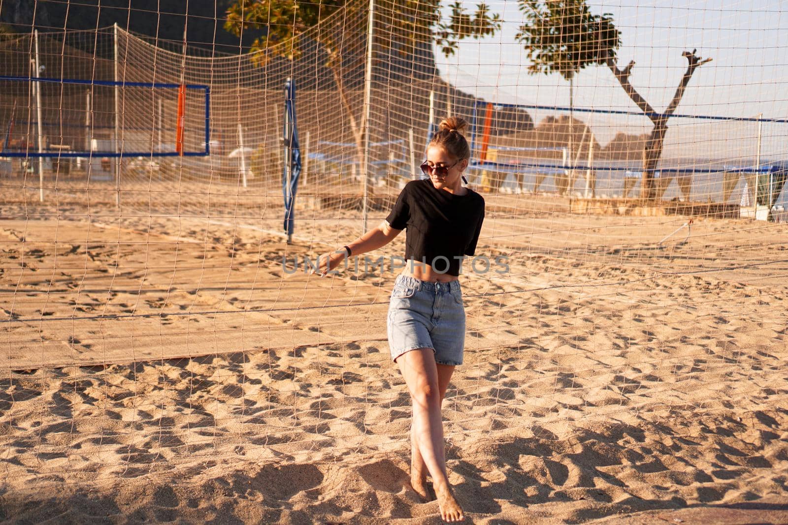 Portrait of attractive woman near volleyball net on the beach by natali_brill