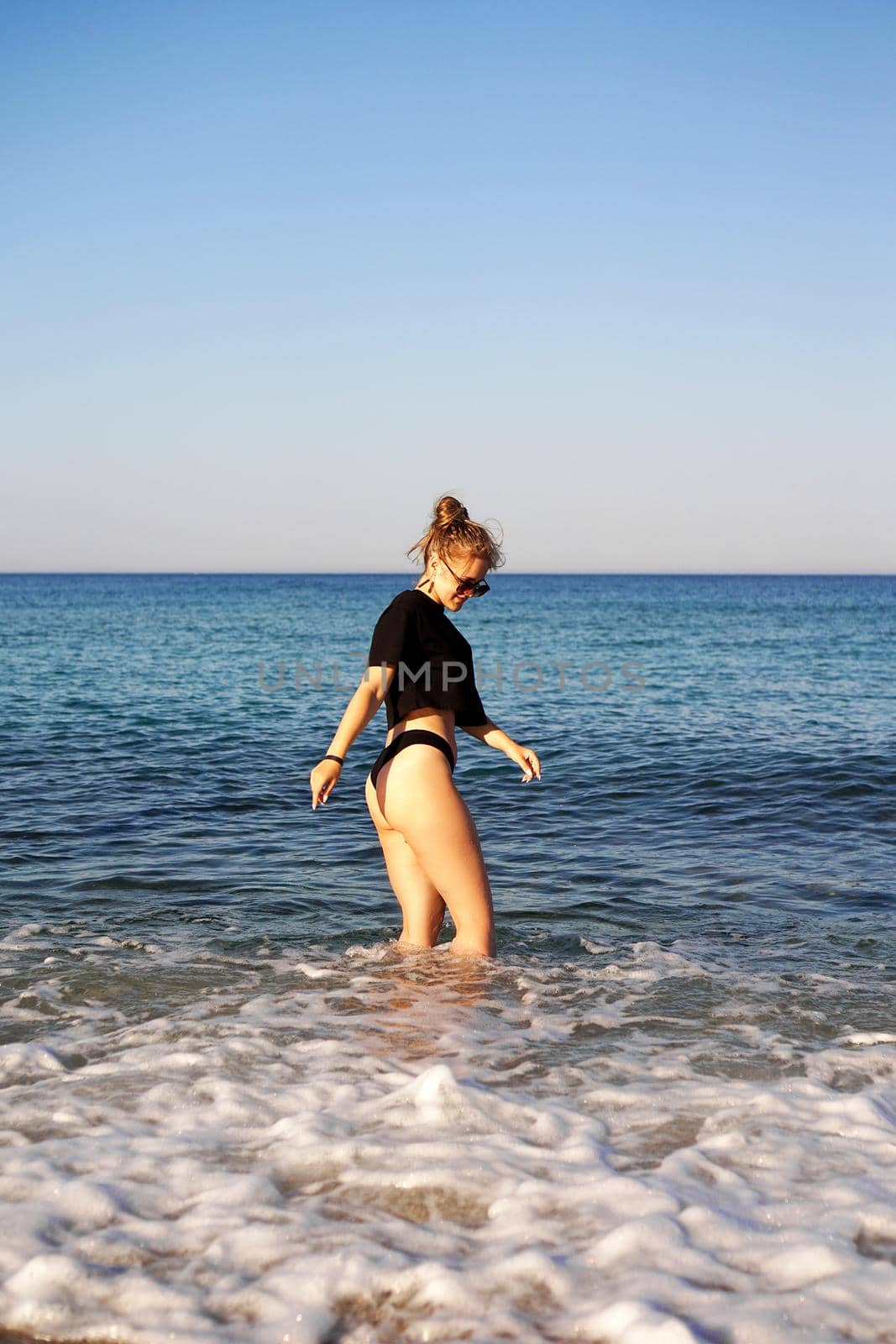 Young woman in a black tank top and underpants on the sea beach by natali_brill