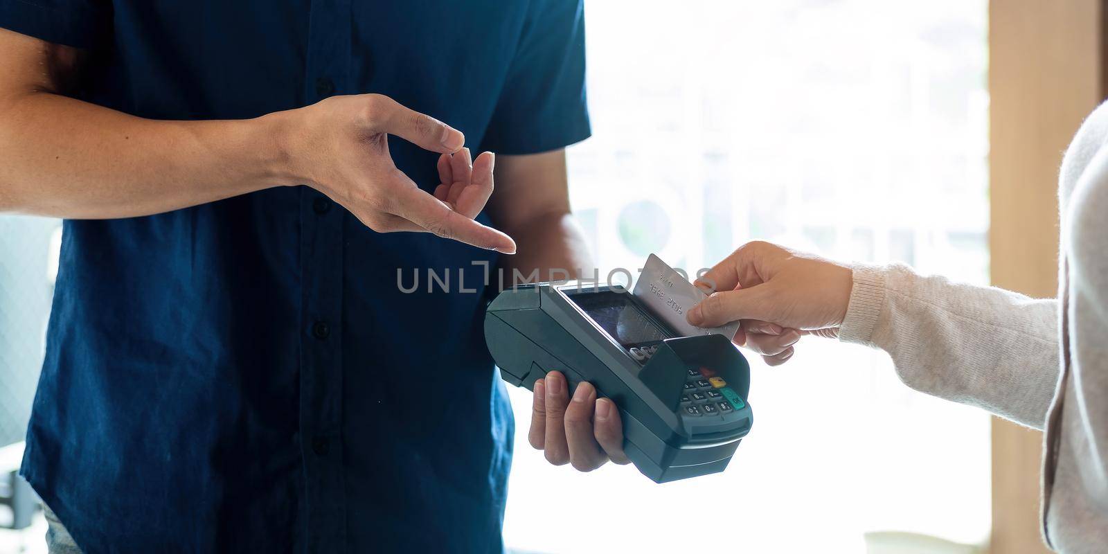 Close up of hand of customer paying with contactless credit card by wichayada