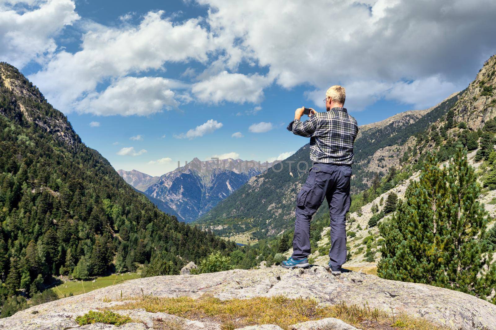Middle aged tourist man take a picture from mountain with mobile phone by Digoarpi