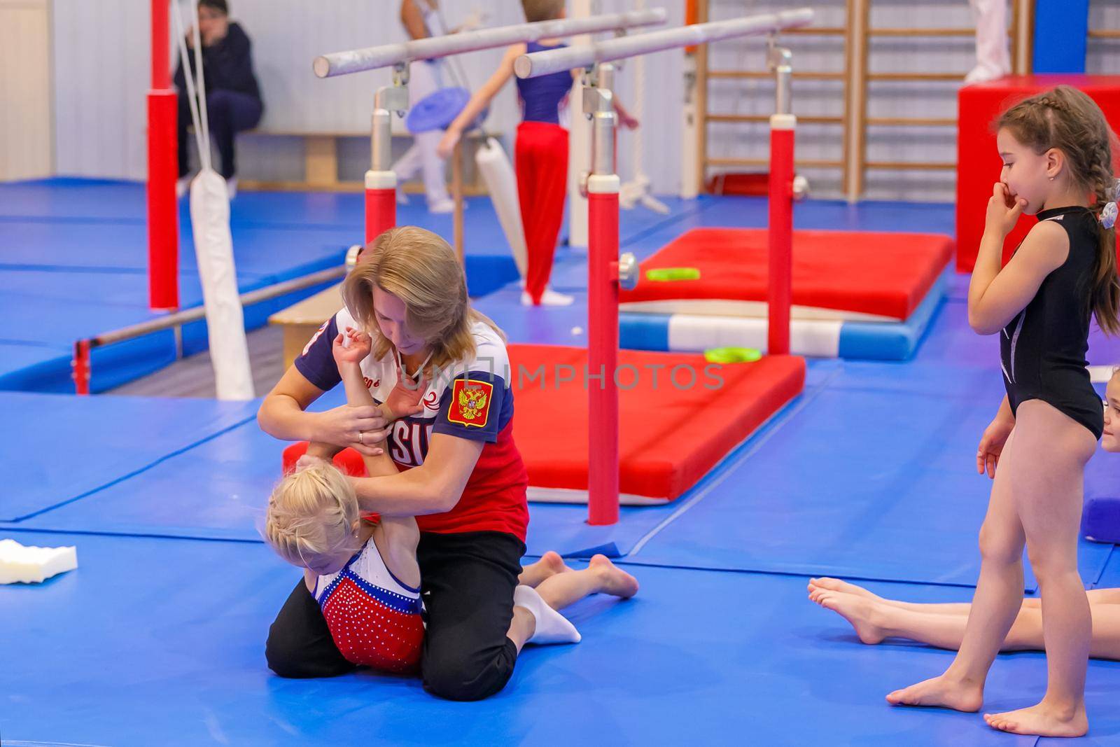Gymnastics coach stretches a young athlete in the gym. Moscow, Russia September 18, 2019 by Yurich32