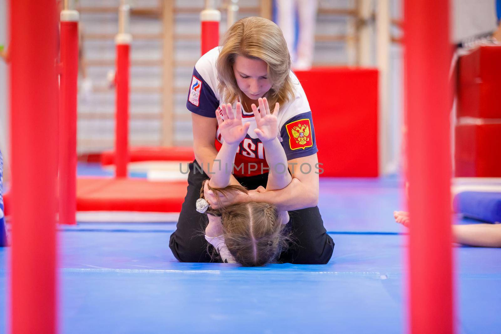 Gymnastics coach stretches a young athlete in the gym. Moscow, Russia September 18, 2019 by Yurich32