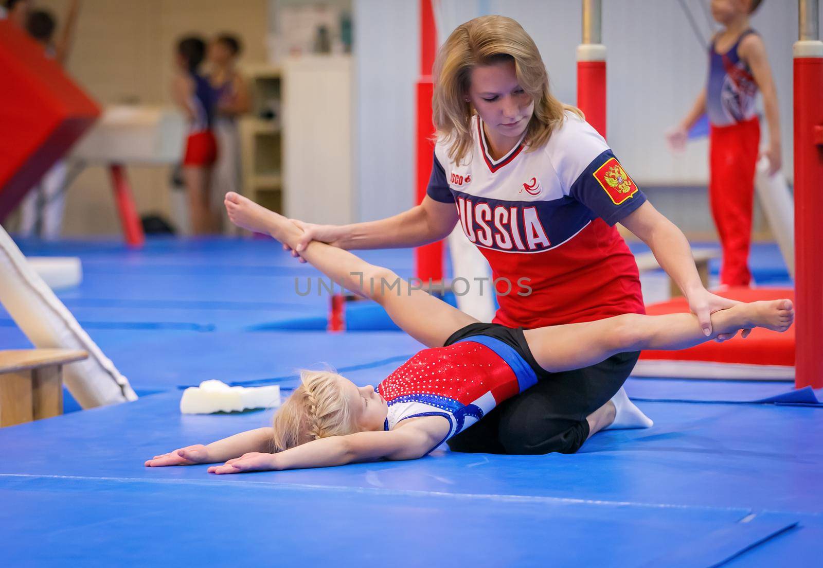 Gymnastics coach stretches a young athlete in the gym. Moscow, Russia September 18, 2019 by Yurich32