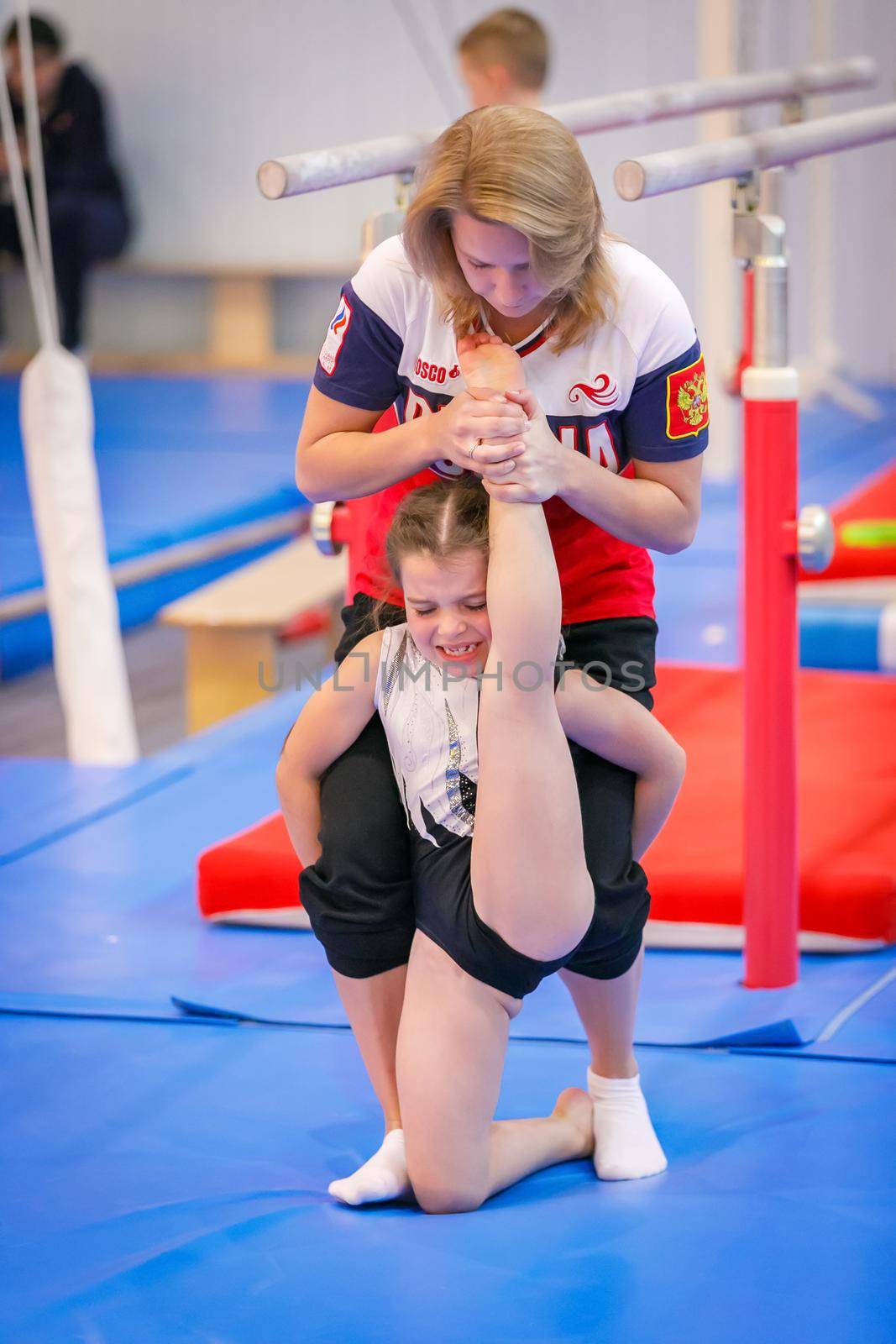 Gymnastics coach stretches a young athlete in the gym. Stretching the legs and arms. The coach prepares the gymnast for the competition. Moscow, Russia September 18, 2019