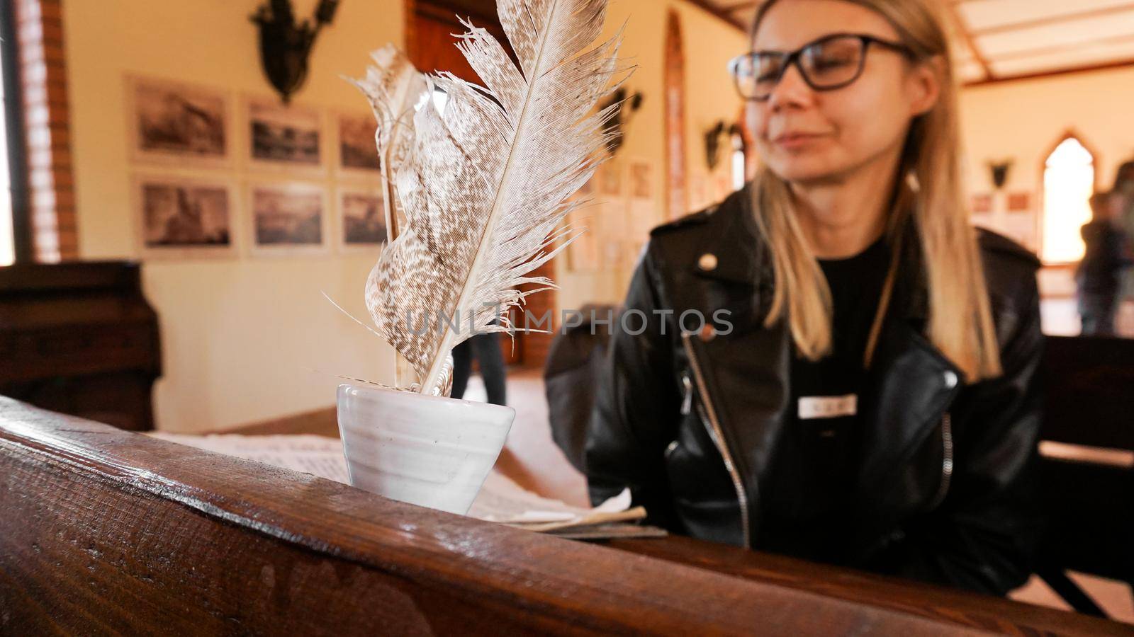 White quill and inkwell in the old university auditorium. Female student with glasses on a blurred background. Medieval atmosphere