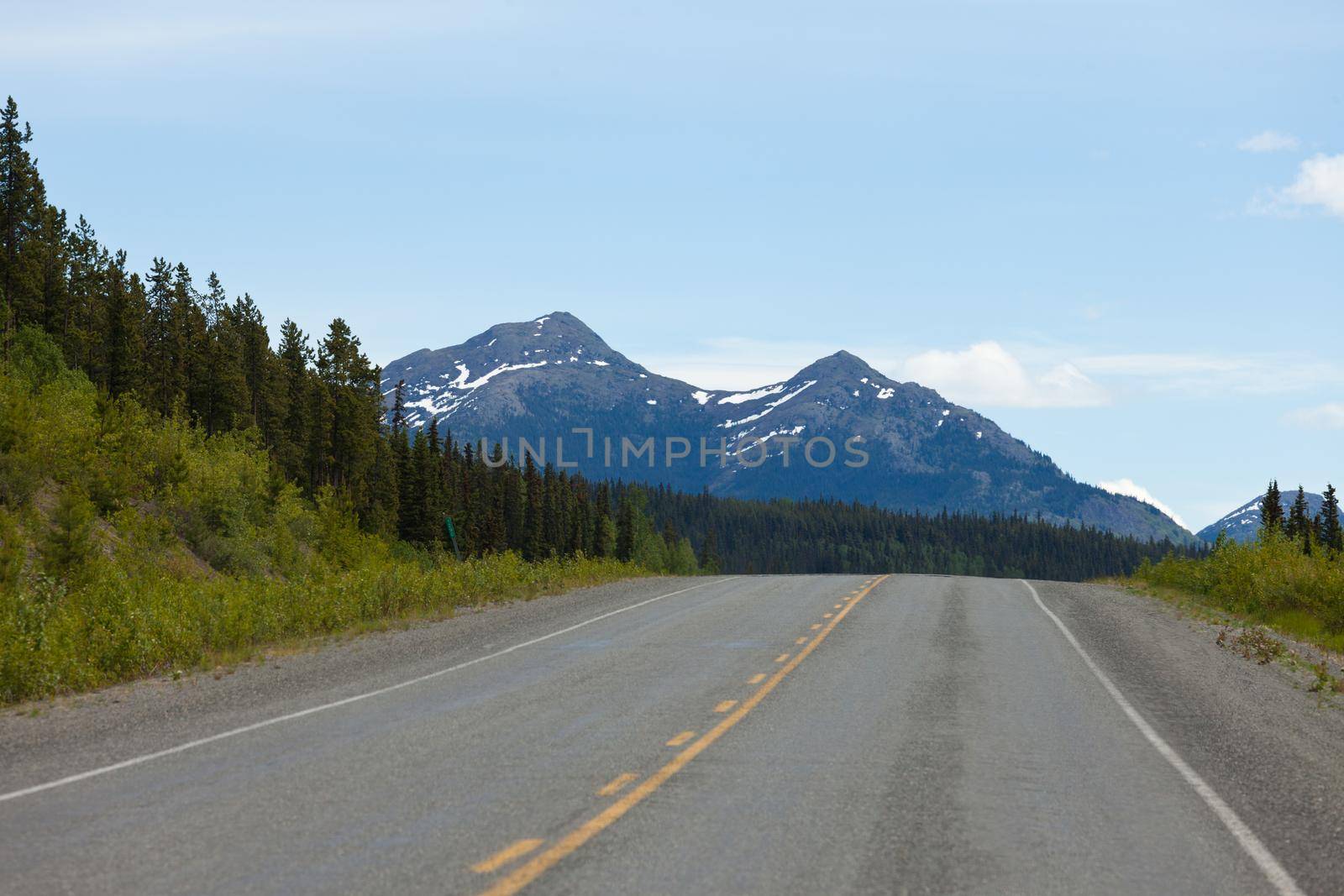 Mountainous wilderness surrounds Alaska Highway at km 1290 north of Teslin, Yukon Territory, Canada
