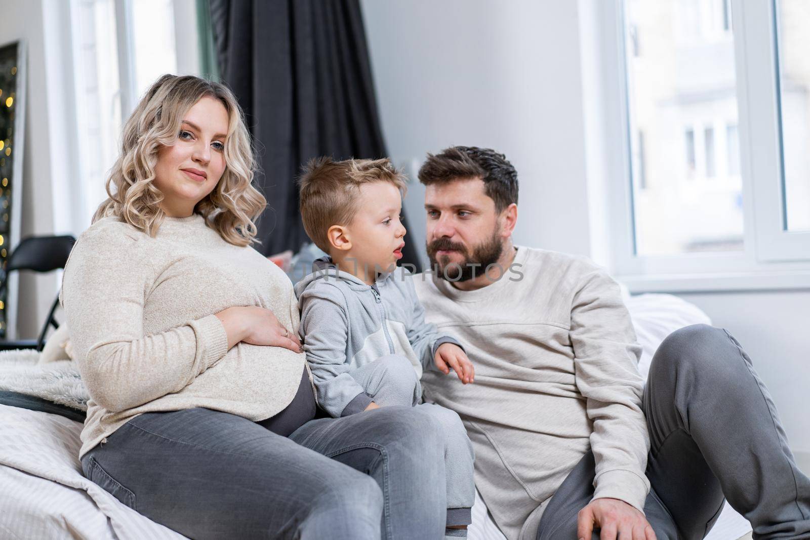 Happy family concept Mother father and little son have fun at home Caucasian family indoors Pregnant mom beard dad and funny little boy