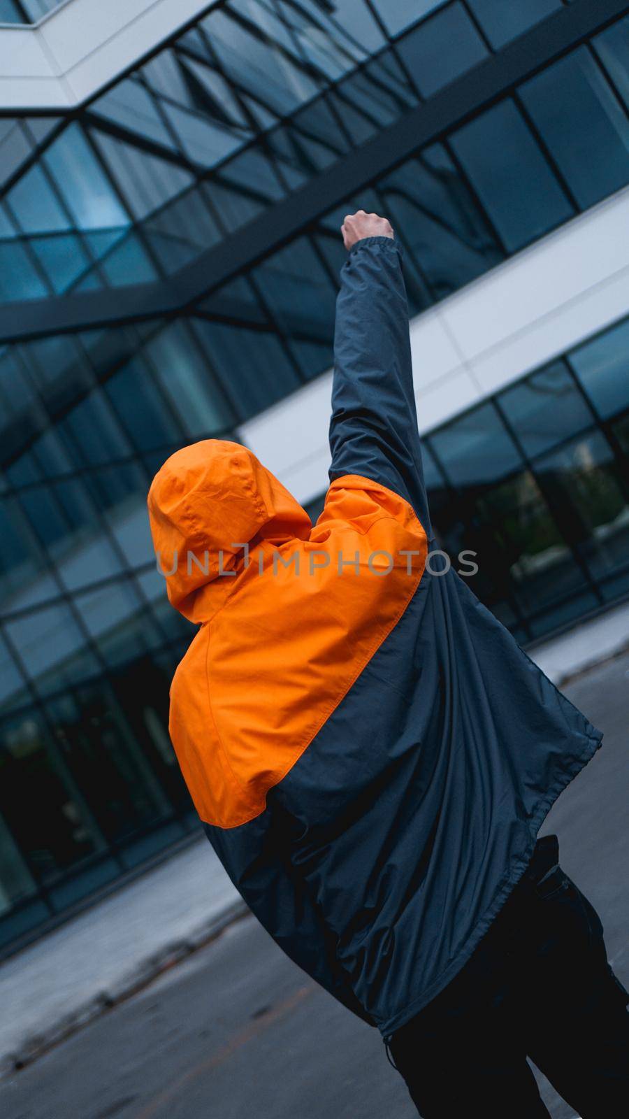 Young man in orange work uniform - glass building on background by natali_brill