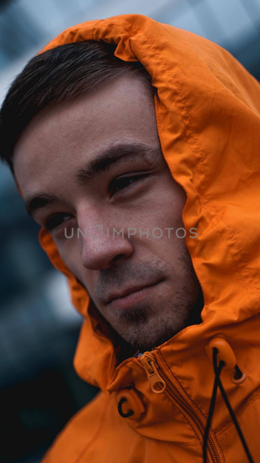Young man in orange work uniform - blue glass building on background